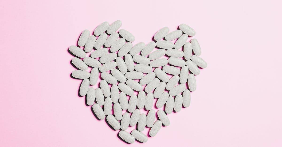 Heart shape made from white tablets on a pink background